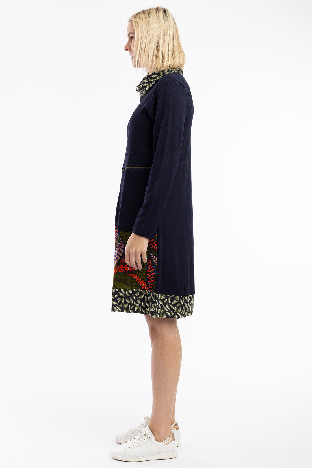 Woman wearing a dark blue dress with patterned sections on a white background