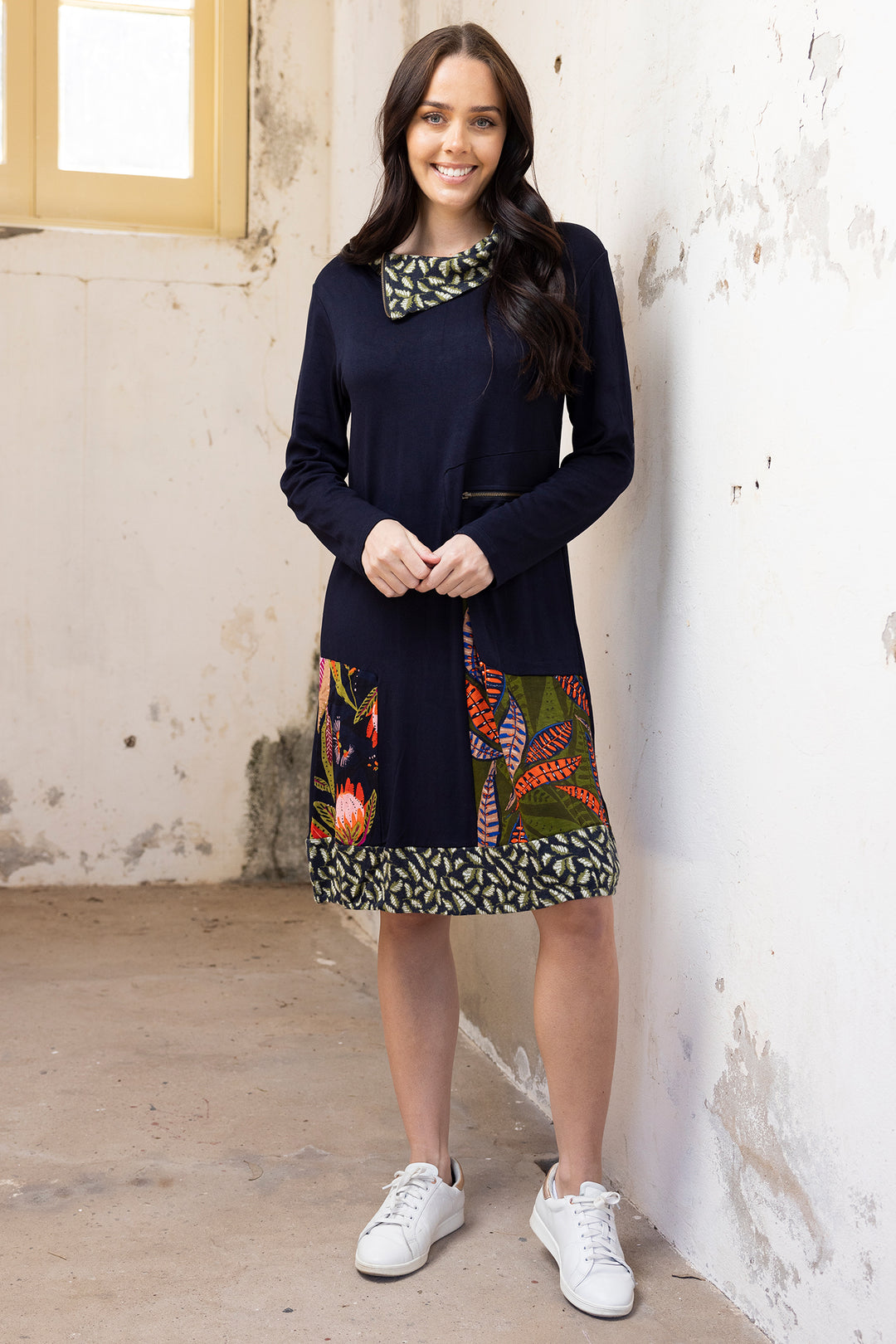 Woman wearing a navy dress with a colorful patchwork skirt in an indoor setting.