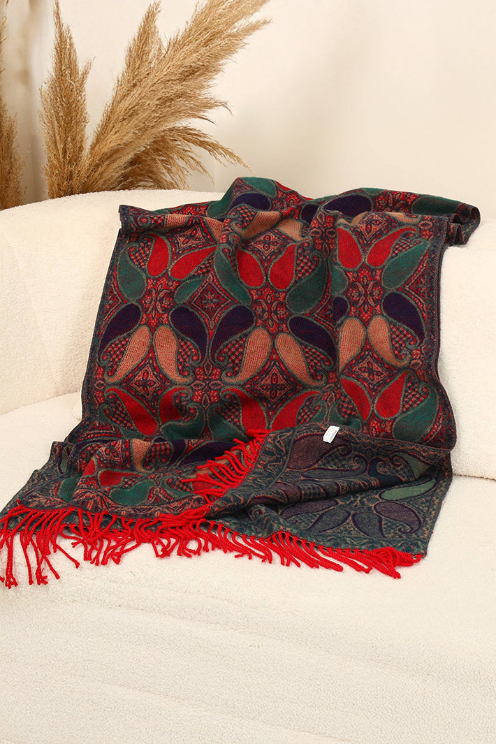 Decorative throw blanket with red and green patterns on a white surface