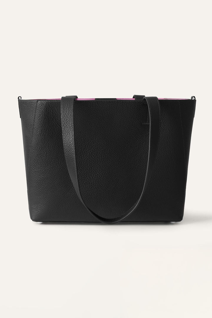 Black handbag with pink interior lining on a light gray background