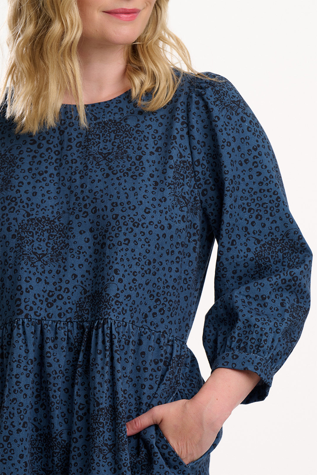 Woman wearing a blue dress with a subtle pattern on a white background