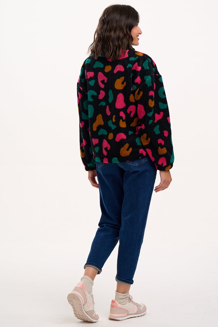 Person wearing a colorful patterned shirt and blue jeans on a white background