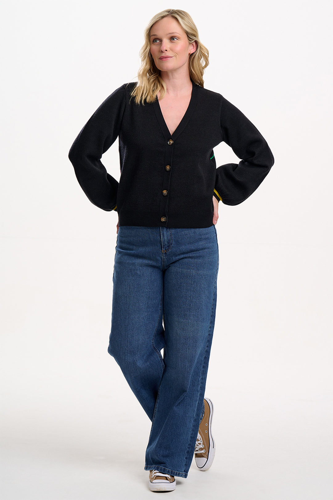 Woman wearing a black cardigan and blue jeans on a white background
