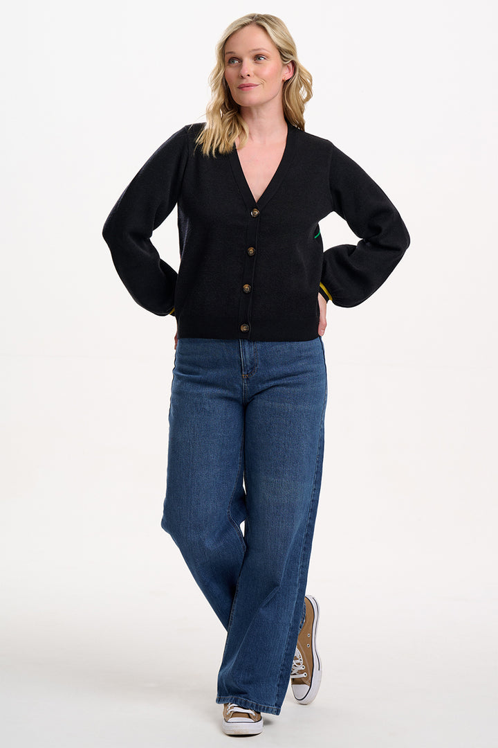 Woman wearing a black cardigan and blue jeans on a white background