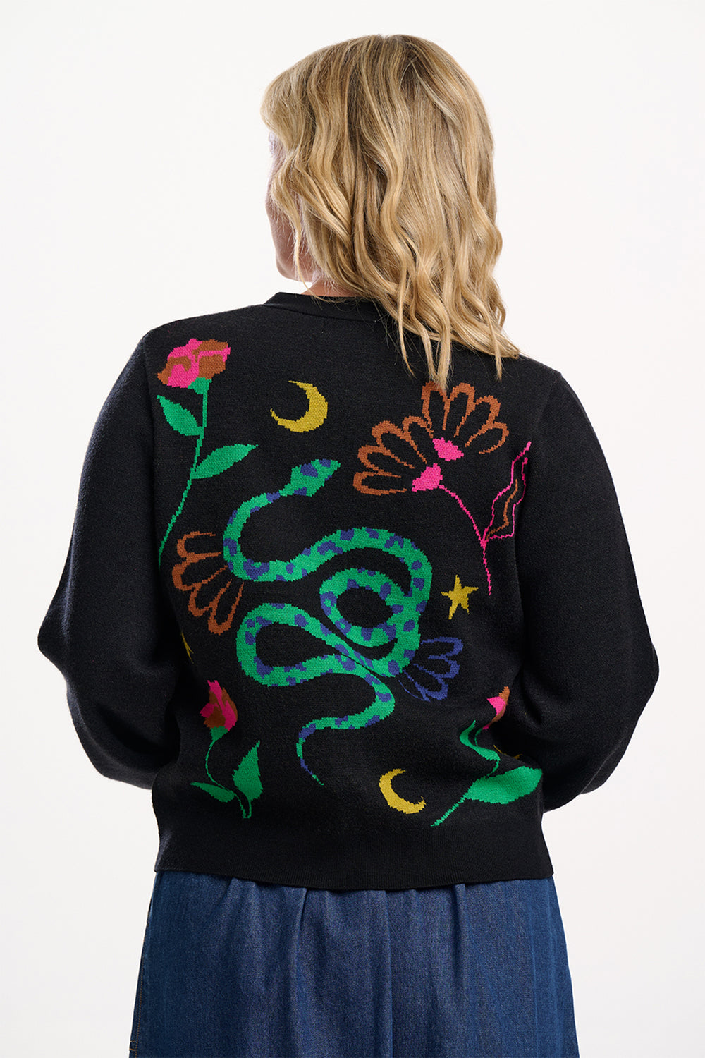 Person wearing a black sweater with colorful snake design on the back