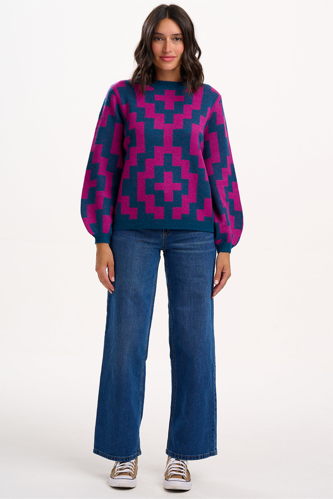 Woman wearing a patterned sweater and jeans on a white background