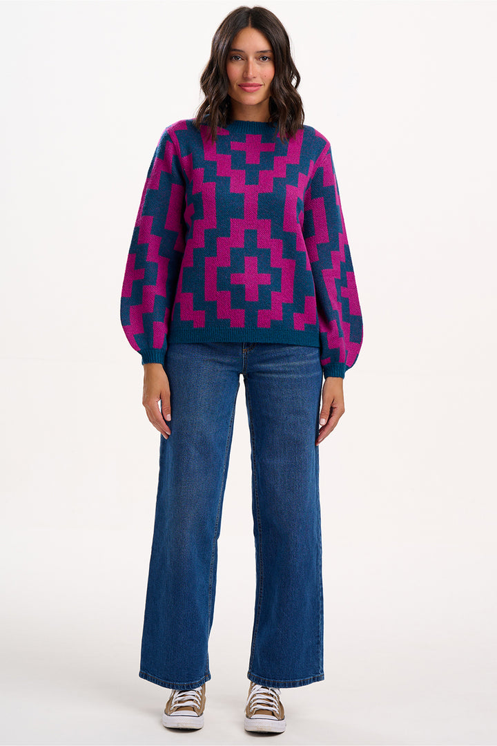 Woman wearing a patterned sweater and jeans on a white background