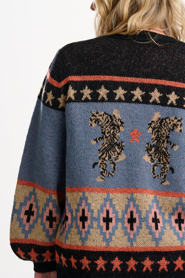 Back view of a person wearing a patterned sweater with animal designs on a plain background