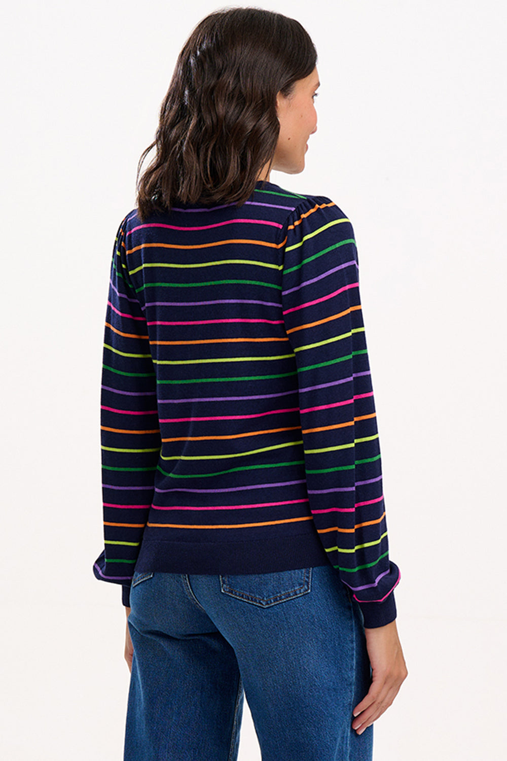Woman wearing a colorful striped sweater and blue jeans on a white background