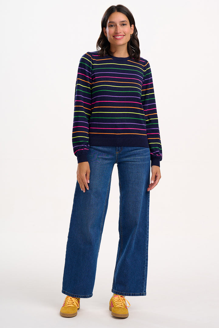 Person wearing a colorful striped sweater and blue jeans on a white background