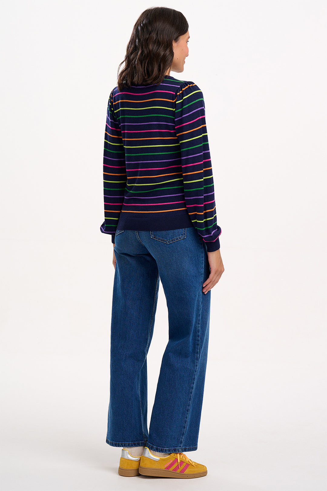 Person wearing a colorful striped sweater and blue jeans on a white background