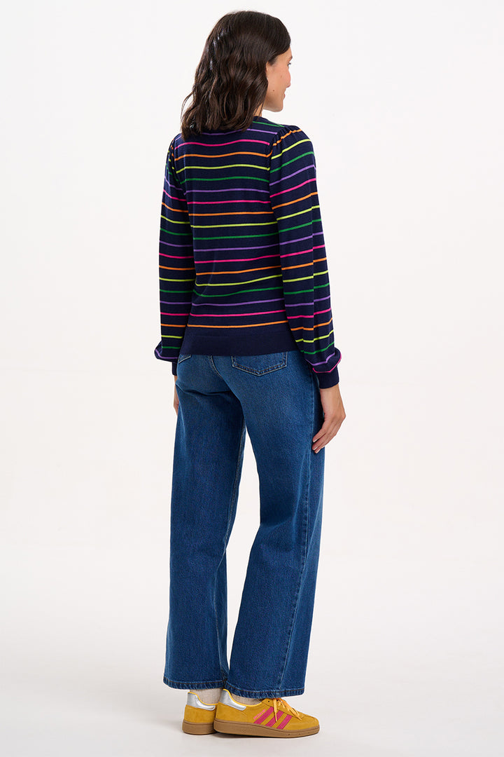 Person wearing a colorful striped sweater and blue jeans on a white background