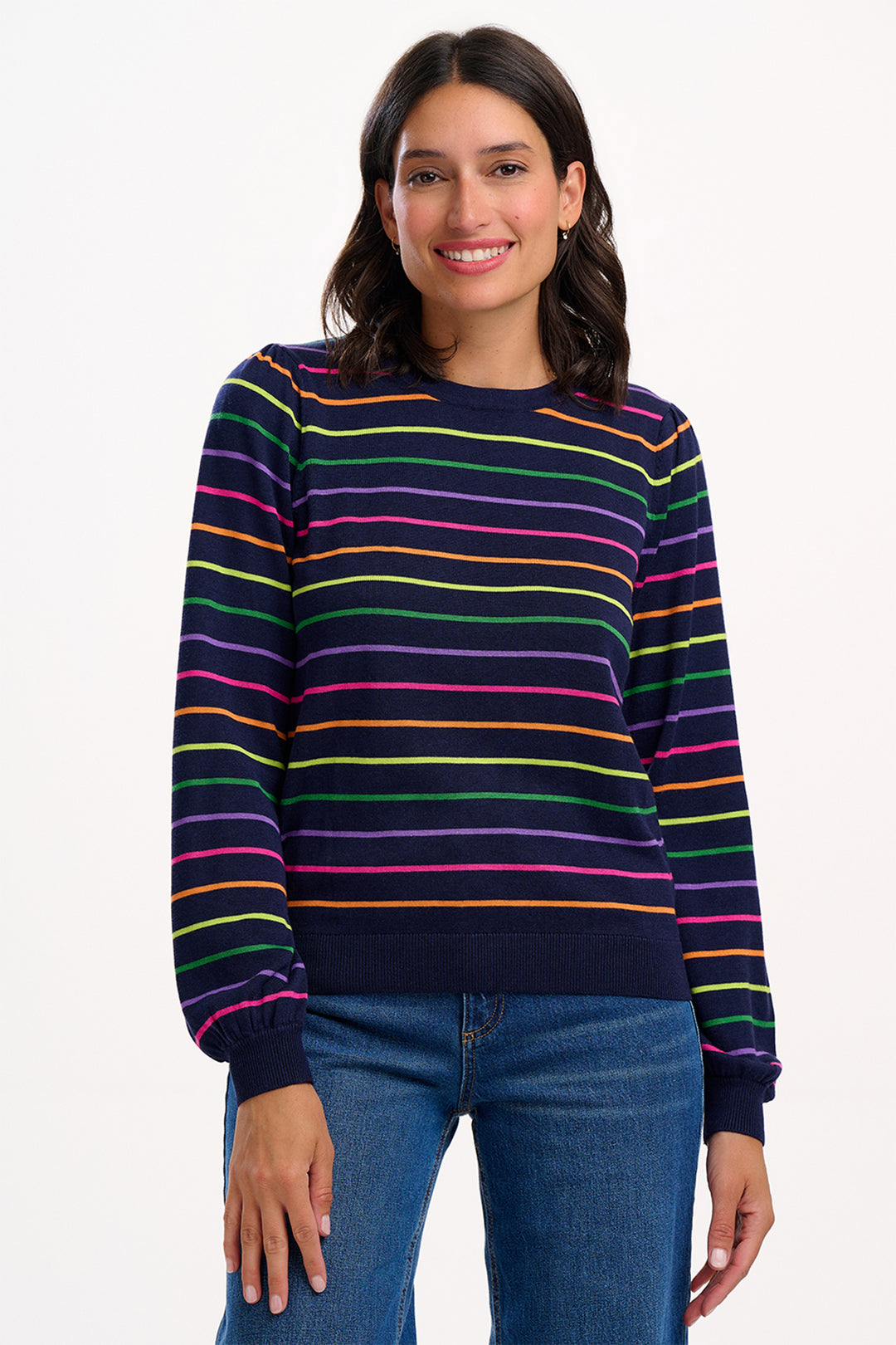 Woman wearing a colorful striped sweater and blue jeans on a white background