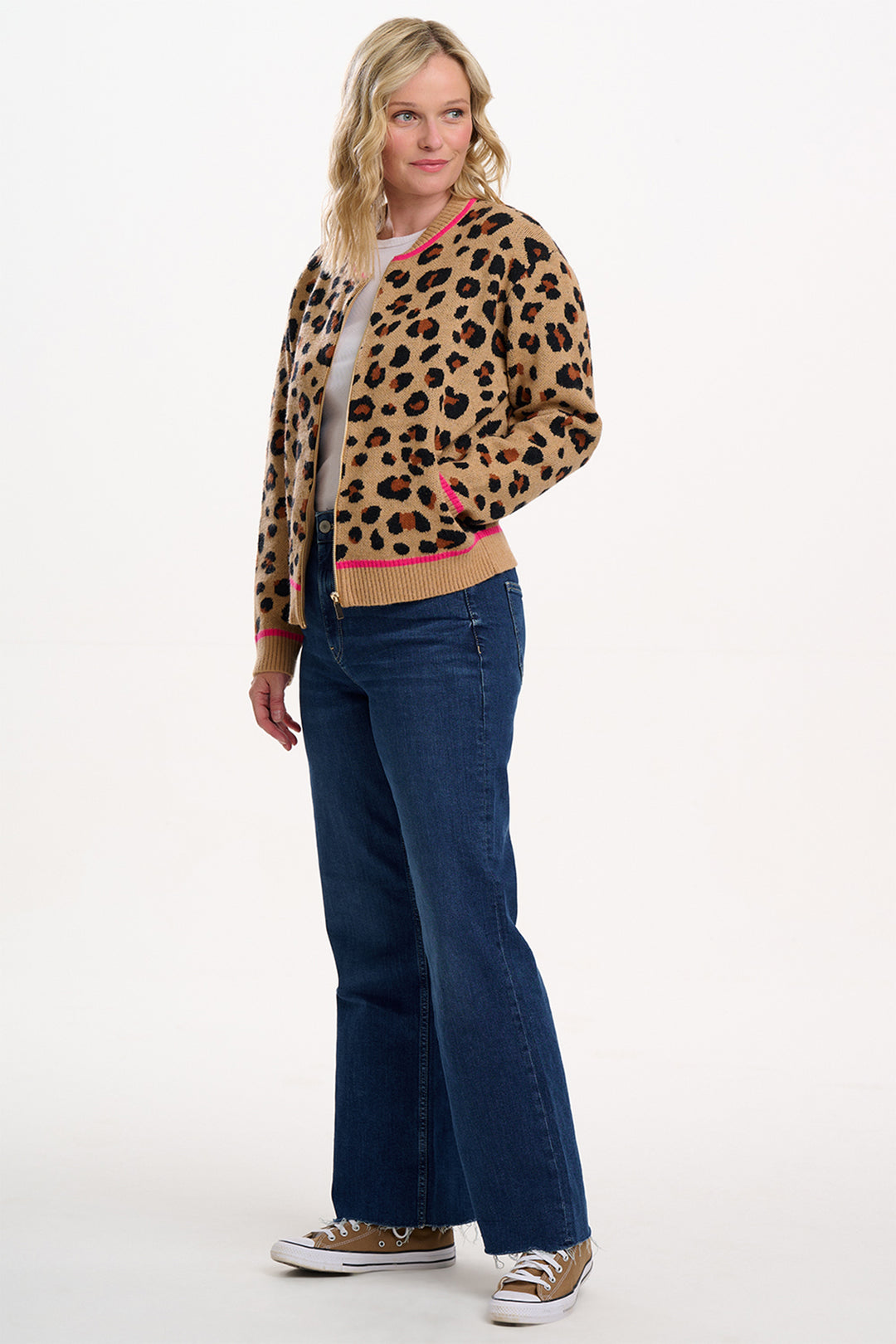 Woman wearing a leopard print cardigan and blue jeans on a white background
