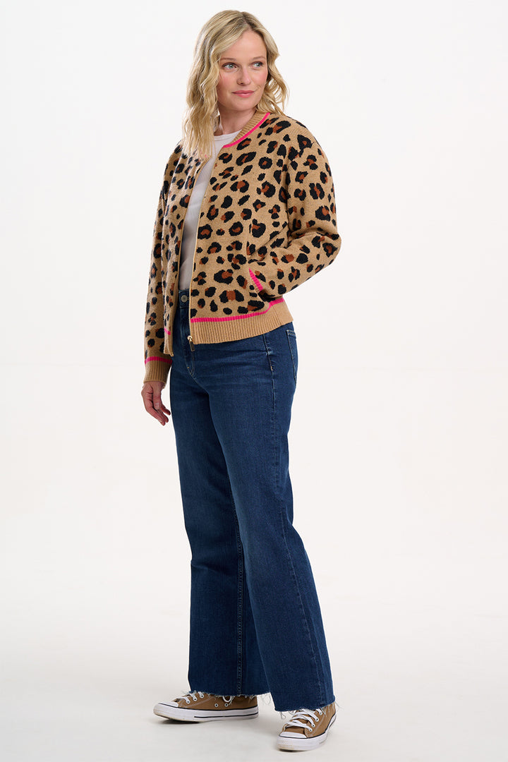 Woman wearing a leopard print cardigan and blue jeans on a white background