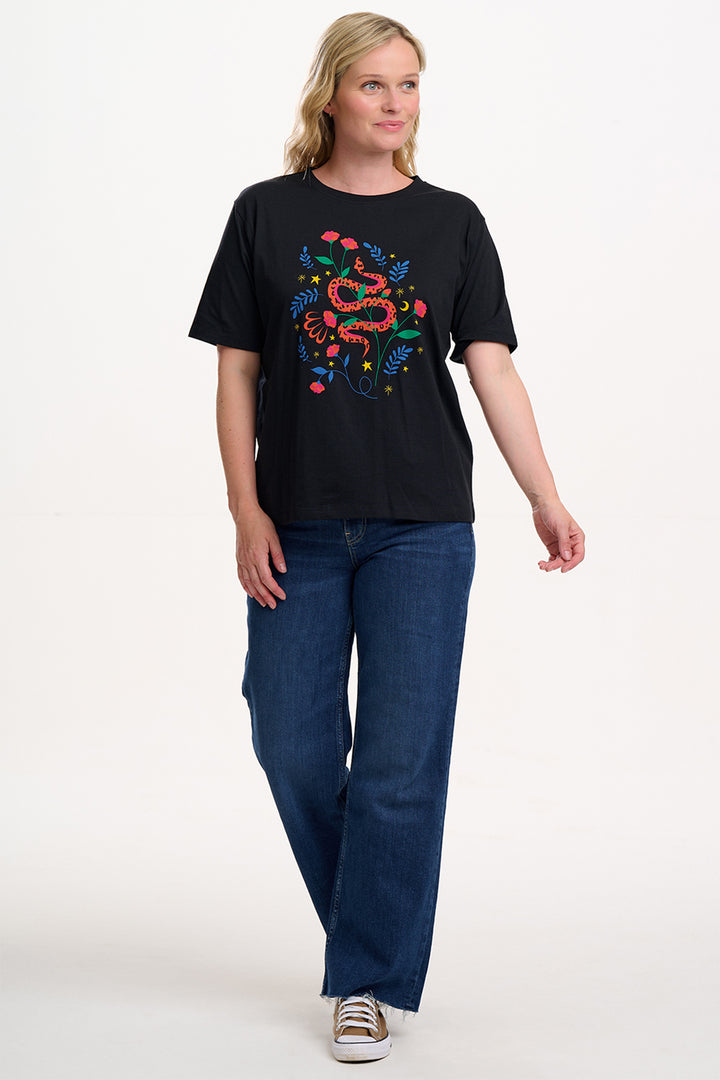 Person wearing a black t-shirt with a colorful snake design on a white background