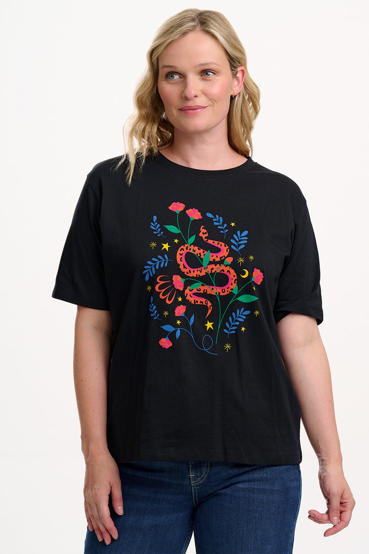 Woman wearing a black t-shirt with colorful snake and floral design on a white background