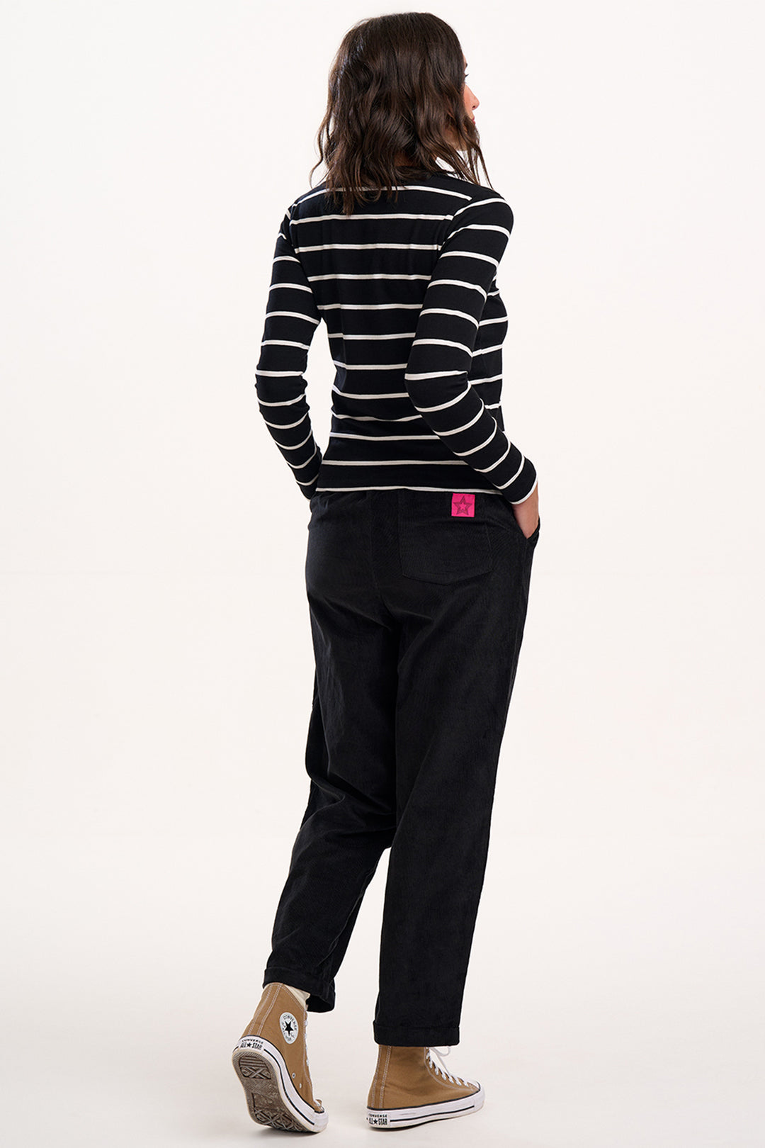 Person wearing a black and white striped shirt and black pants on a white background