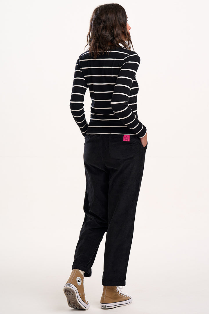 Person wearing a black and white striped shirt and black pants on a white background