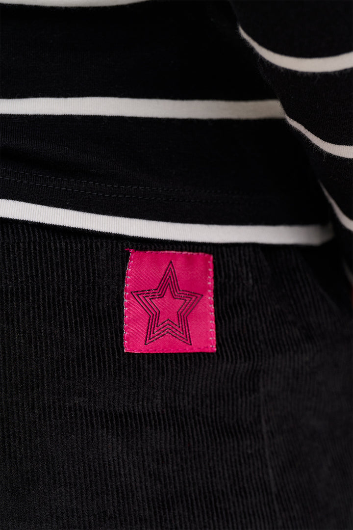 Close-up of a black and white striped garment with a pink label featuring a star design.