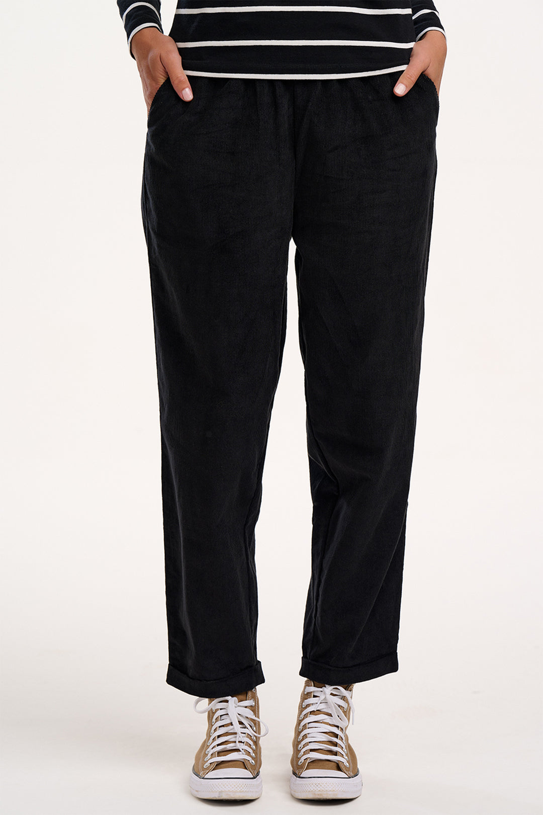Person wearing black pants and a striped shirt on a white background