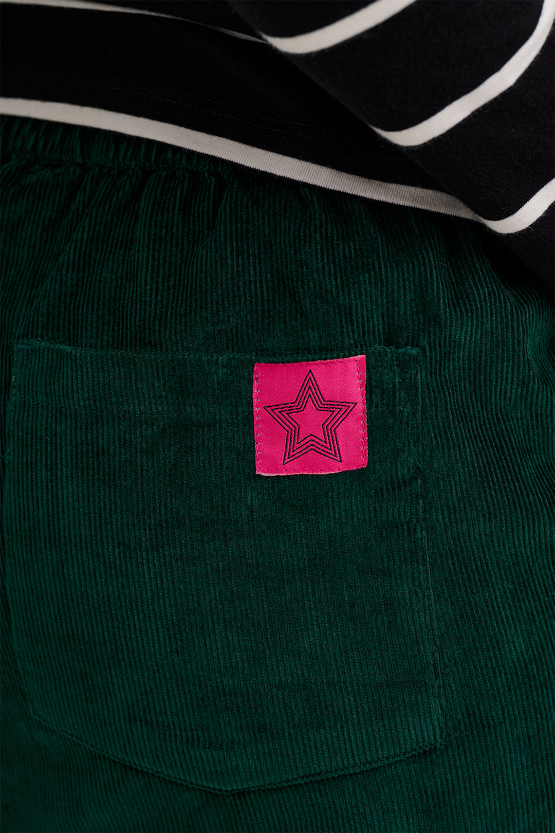 Green corduroy jacket with a pink label featuring a star design.