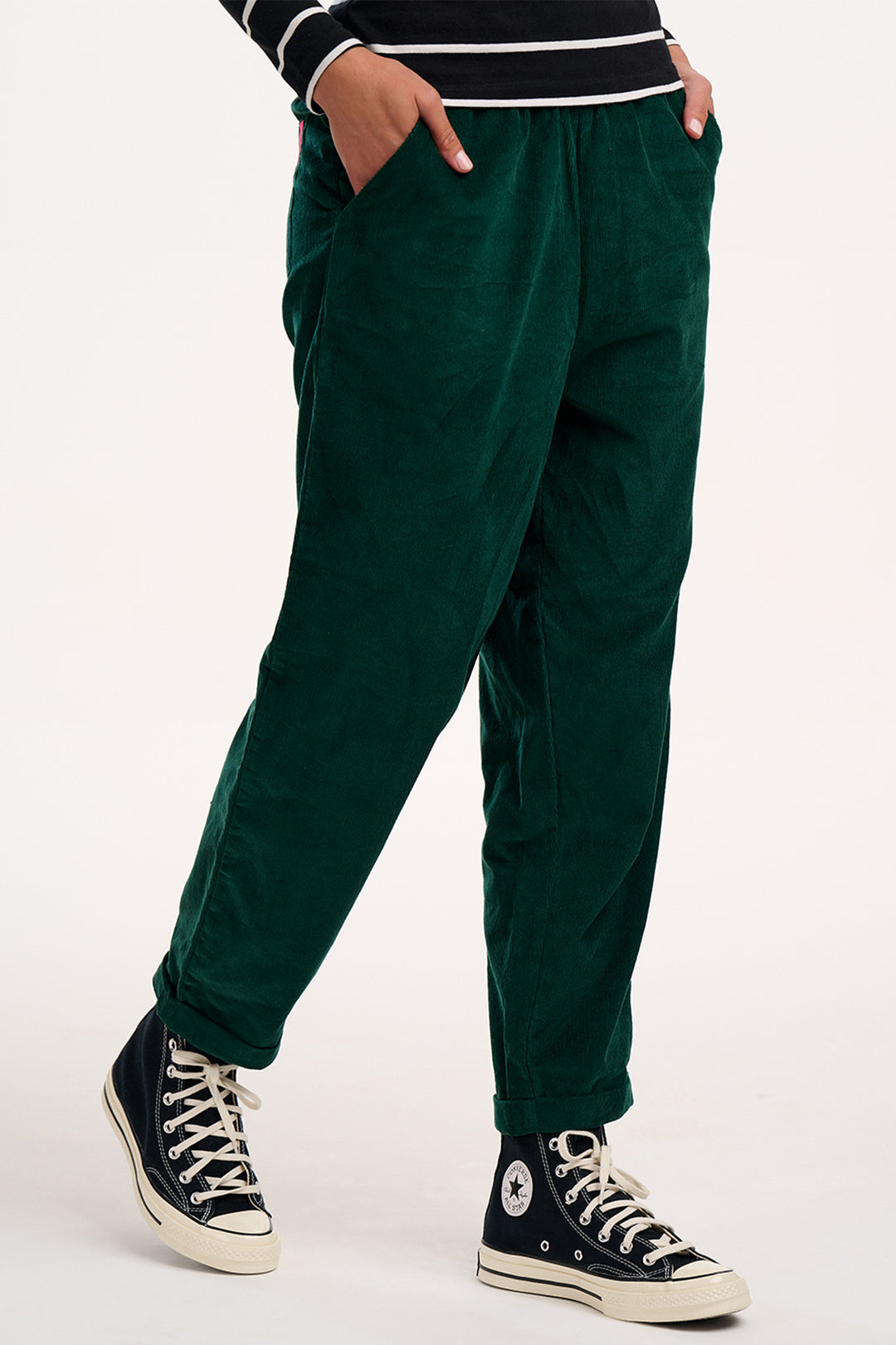 Person wearing green pants and black sneakers on a white background
