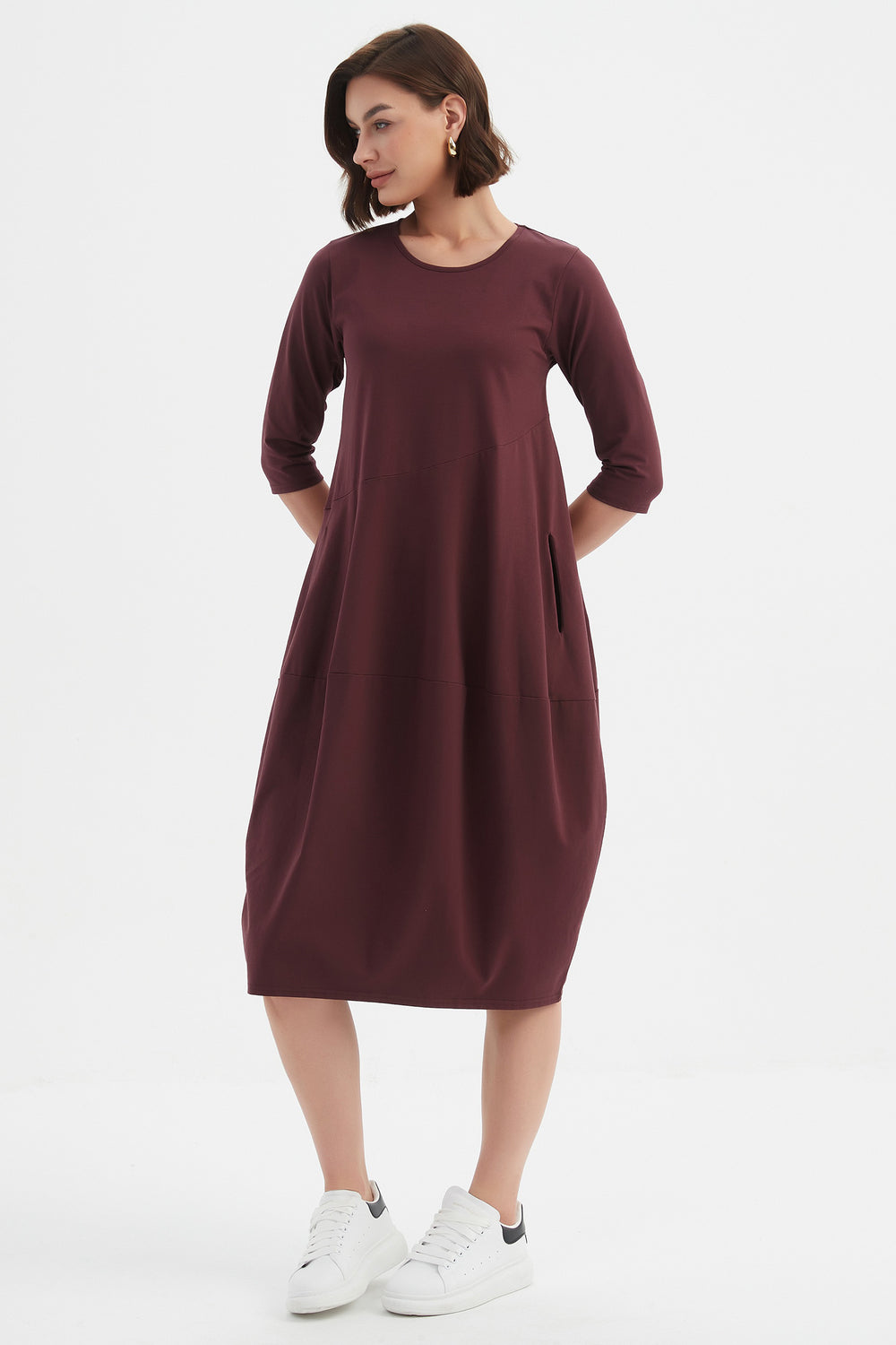 Woman wearing a burgundy dress with white sneakers on a white background