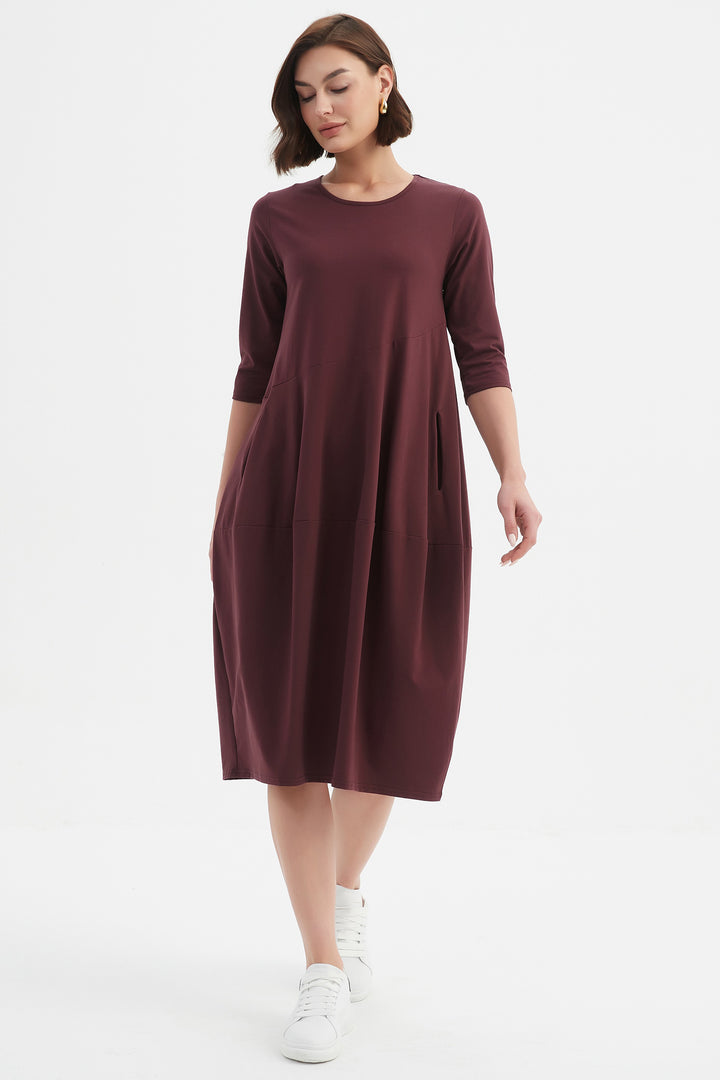 Woman wearing a maroon dress on a white background