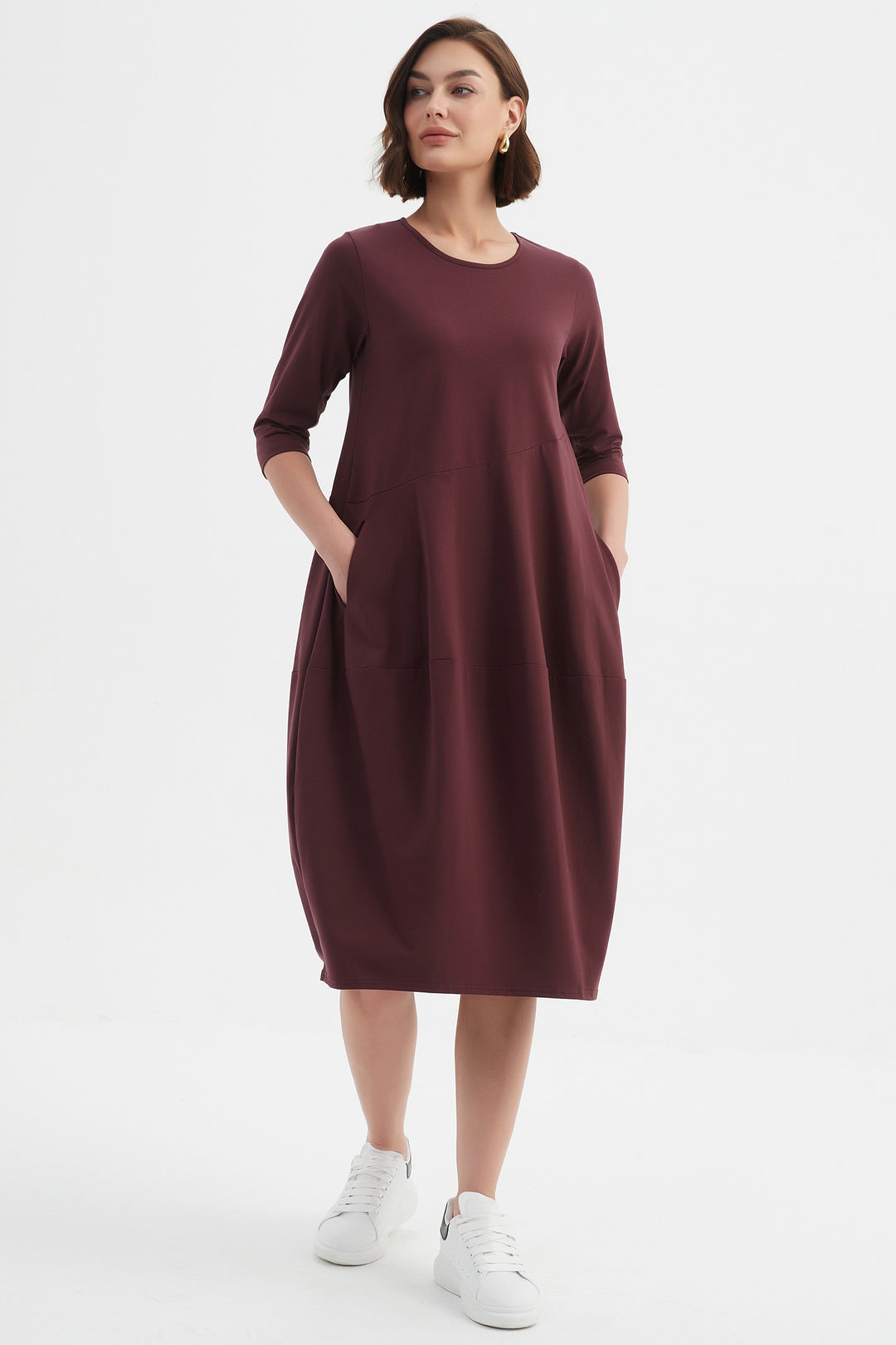 Woman wearing a burgundy dress with white sneakers on a white background