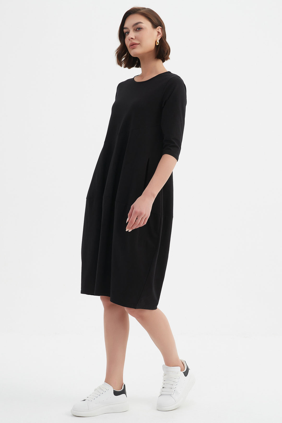 Woman wearing a black dress with white sneakers on a white background
