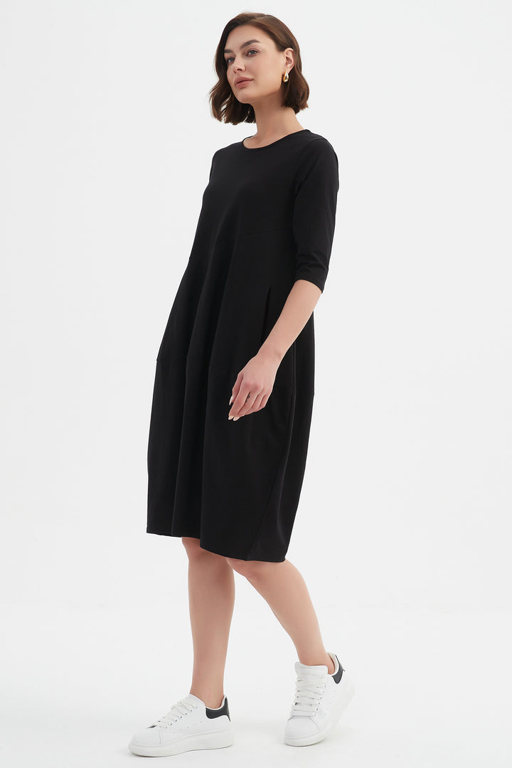 Woman wearing a black dress with white sneakers on a white background