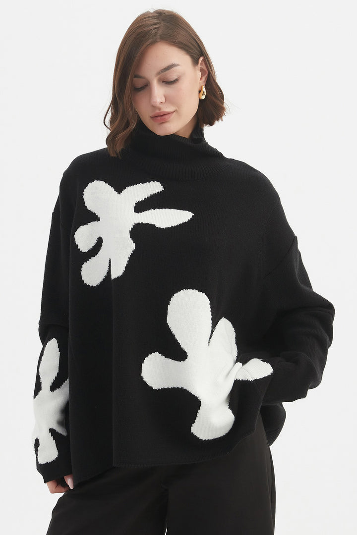 Person wearing a black sweater with white abstract patterns on a white background