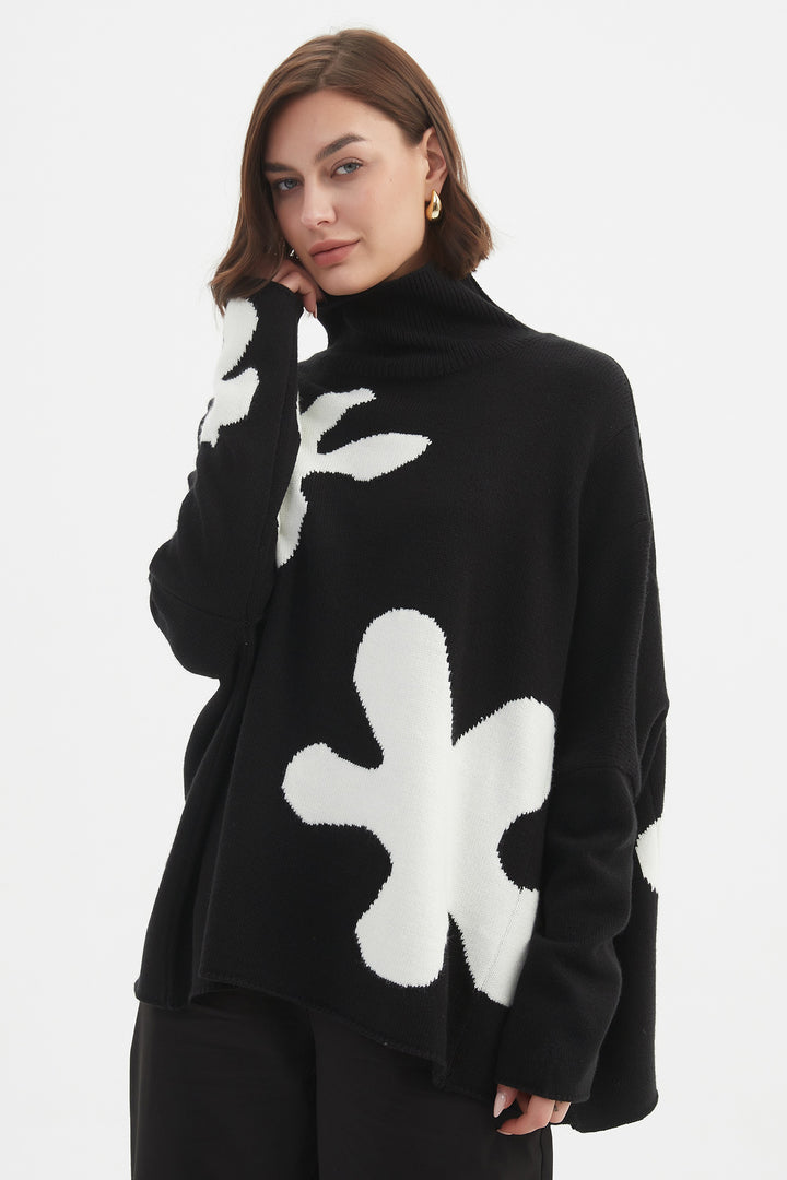 Person wearing a black sweater with white floral patterns on a white background