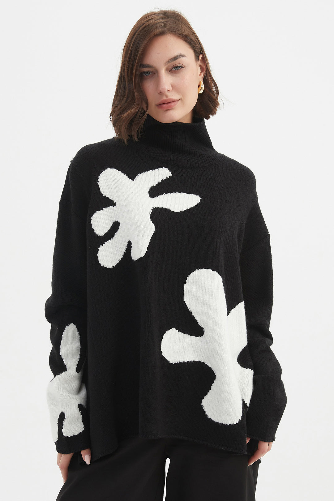 Person wearing a black sweater with white abstract patterns on a white background