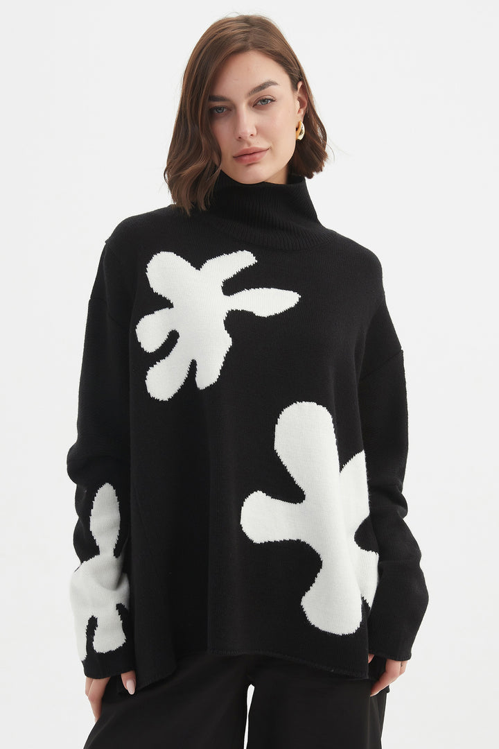 Person wearing a black sweater with white abstract patterns on a white background