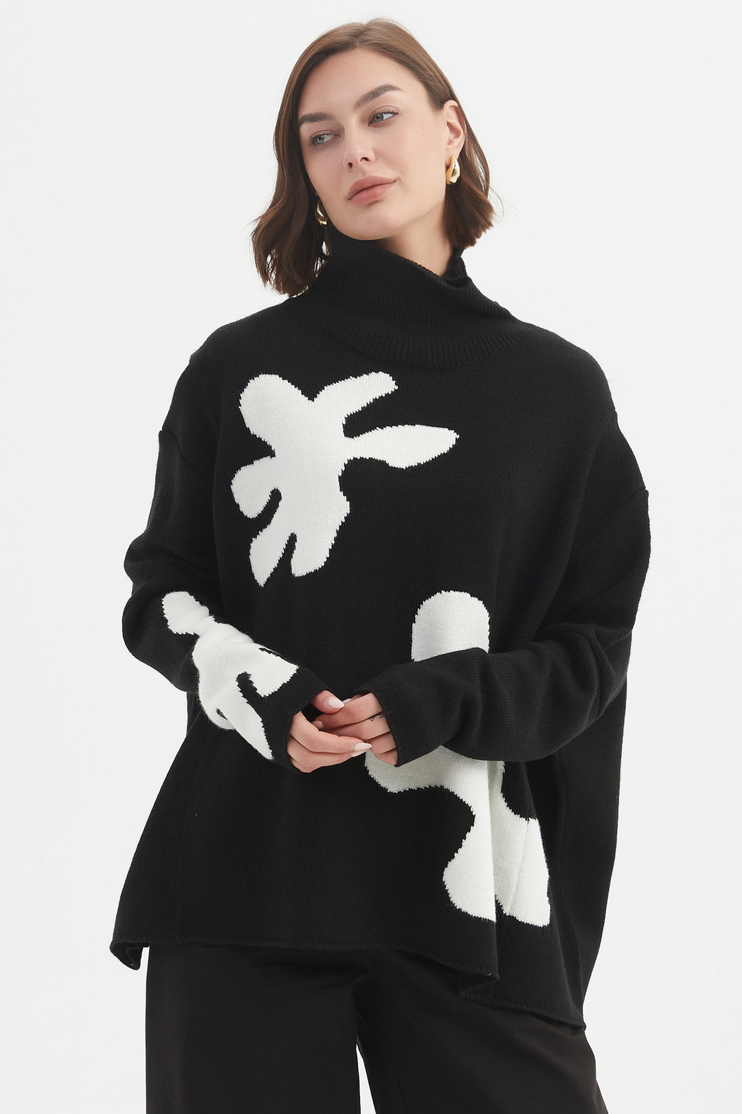 Person wearing a black sweater with white abstract designs on a plain background