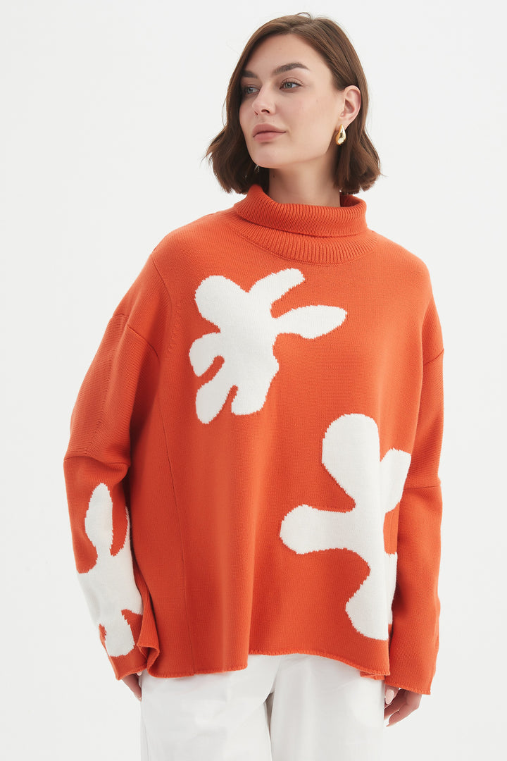 Person wearing an orange sweater with white abstract patterns on a plain background