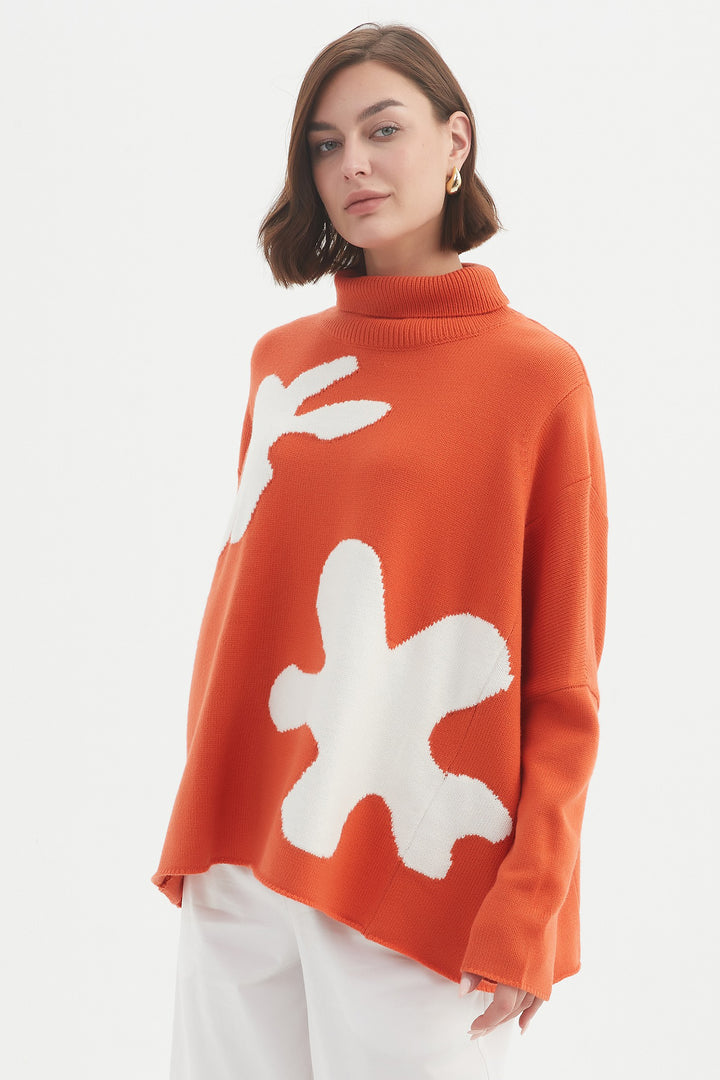 Person wearing an orange sweater with white abstract designs on a white background