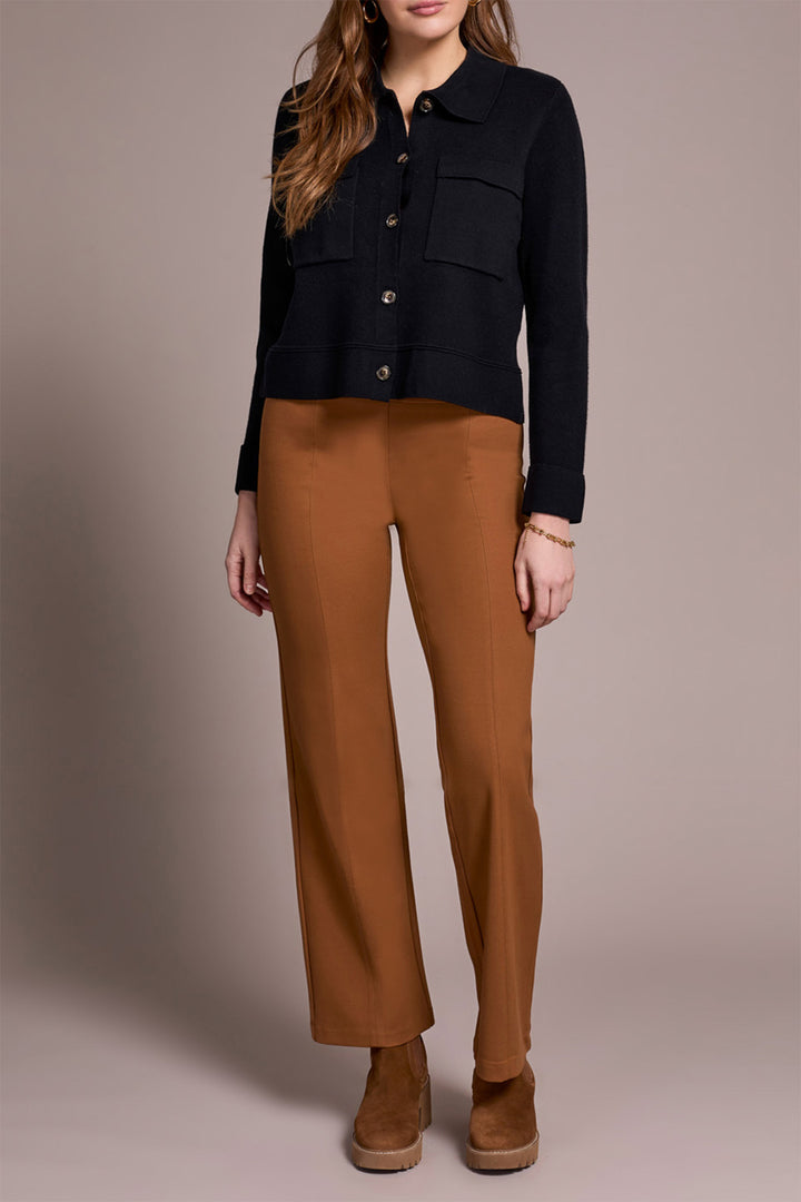 Person wearing a black jacket and brown pants on a neutral background