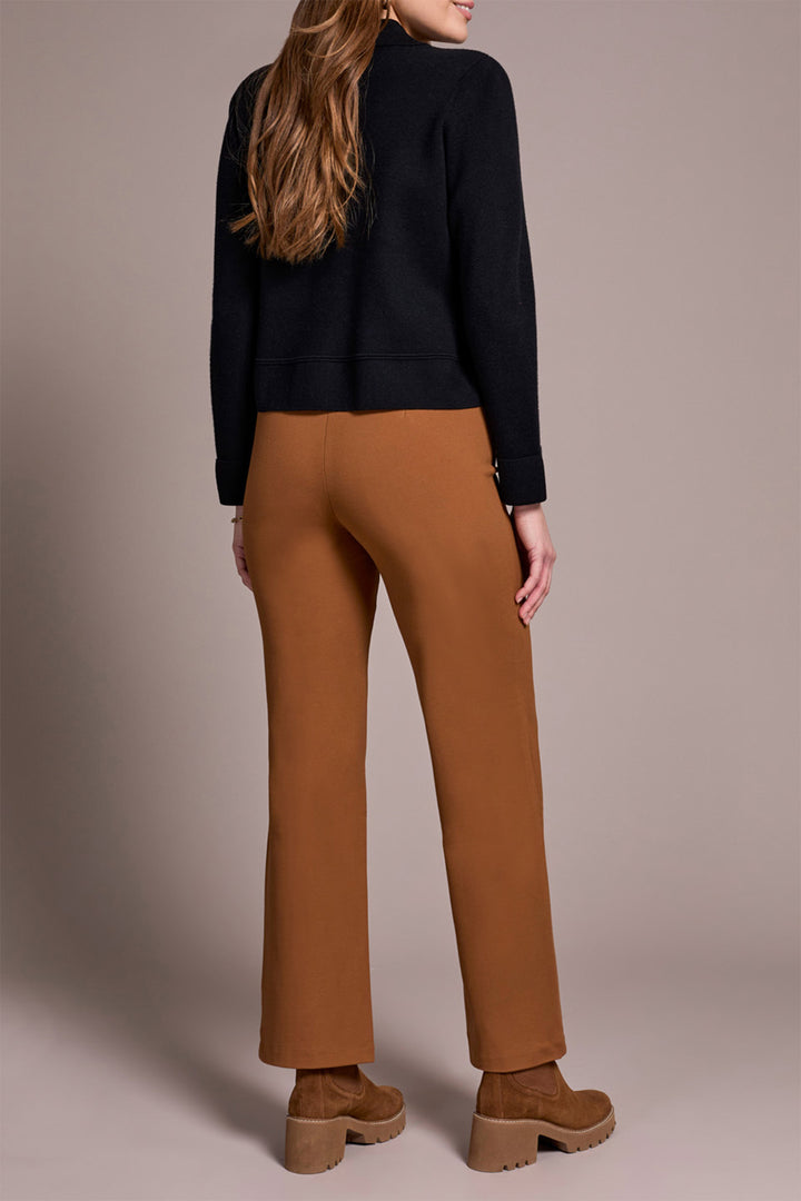 Person wearing a black top and brown pants on a beige background