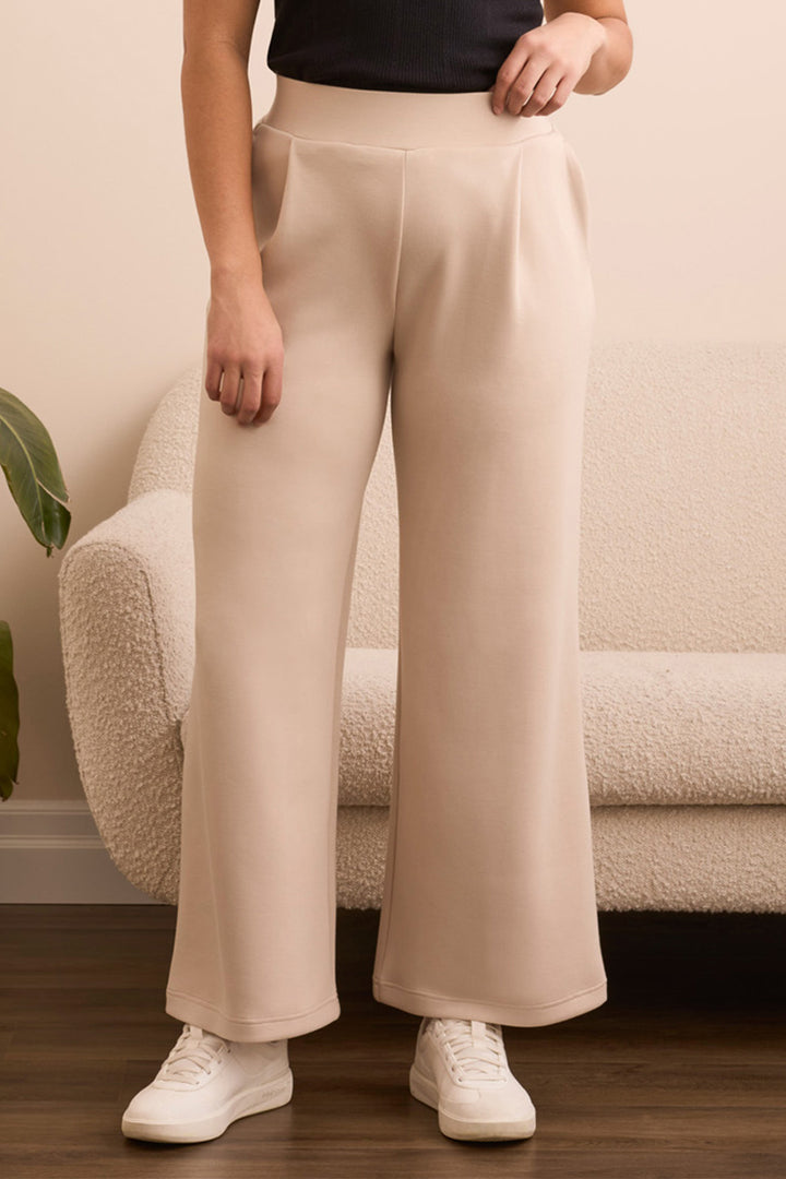 Person wearing beige wide-leg pants and white sneakers in a living room setting.
