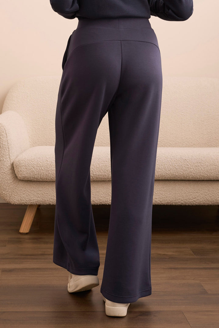 Person wearing dark blue pants standing in a room with a beige sofa.