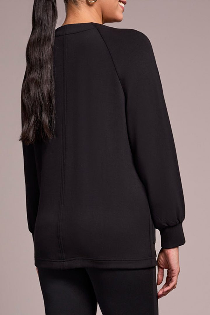 Person wearing a black long-sleeve top against a neutral background