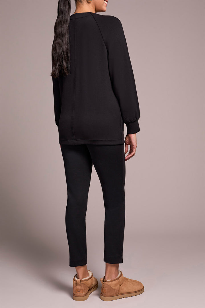 Person wearing a black outfit with brown shoes on a plain background