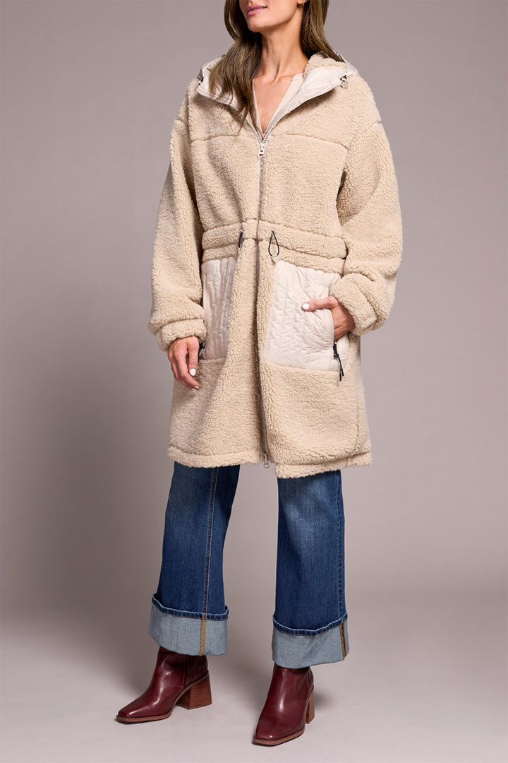 Person wearing a beige fleece coat with a gray background