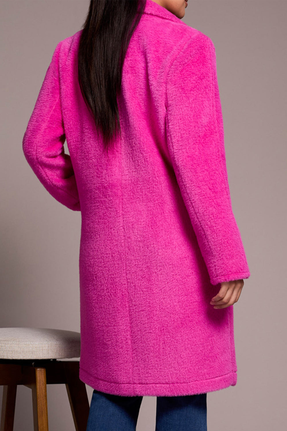 Person wearing a bright pink coat against a neutral background