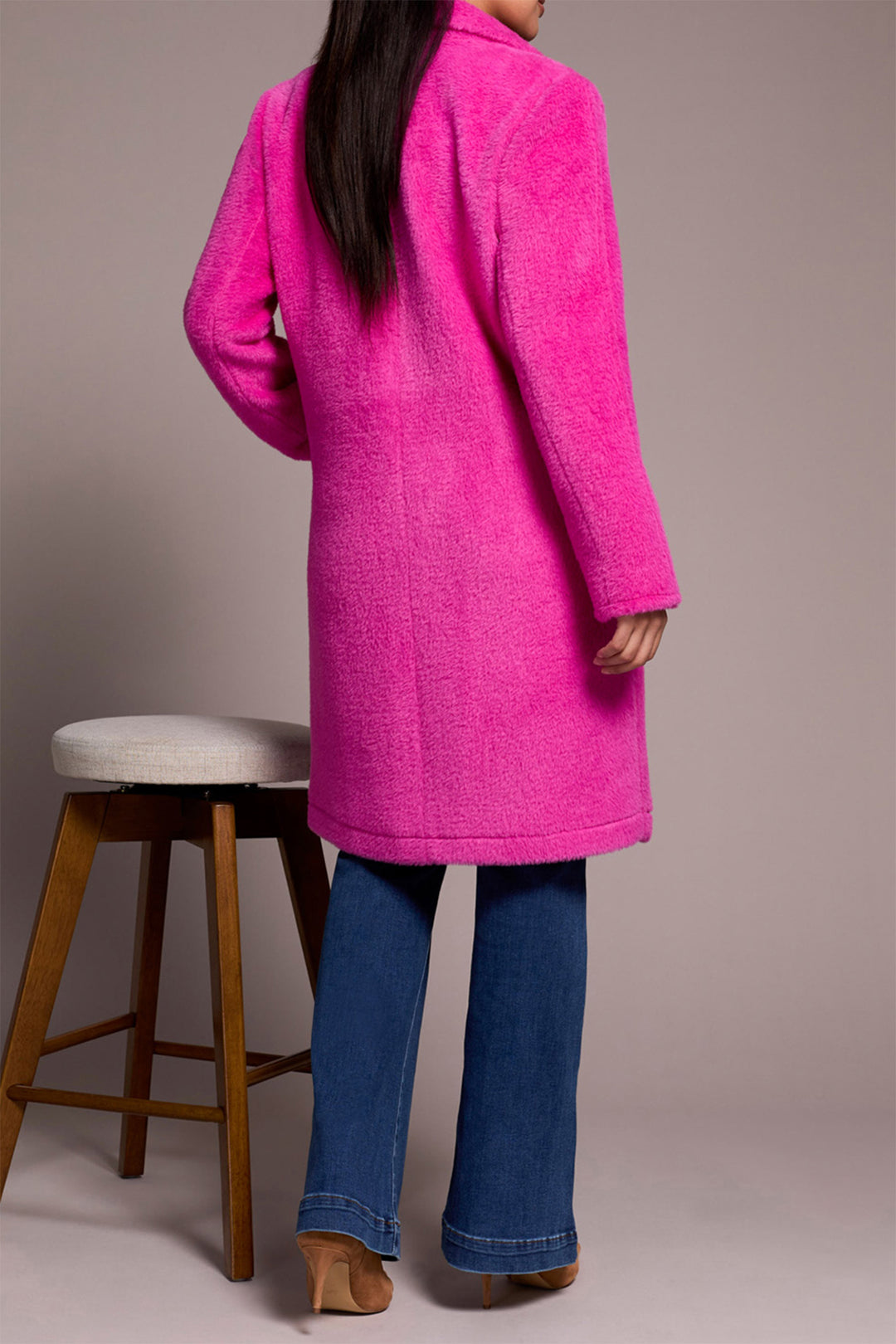 Person wearing a bright pink coat with a plain background