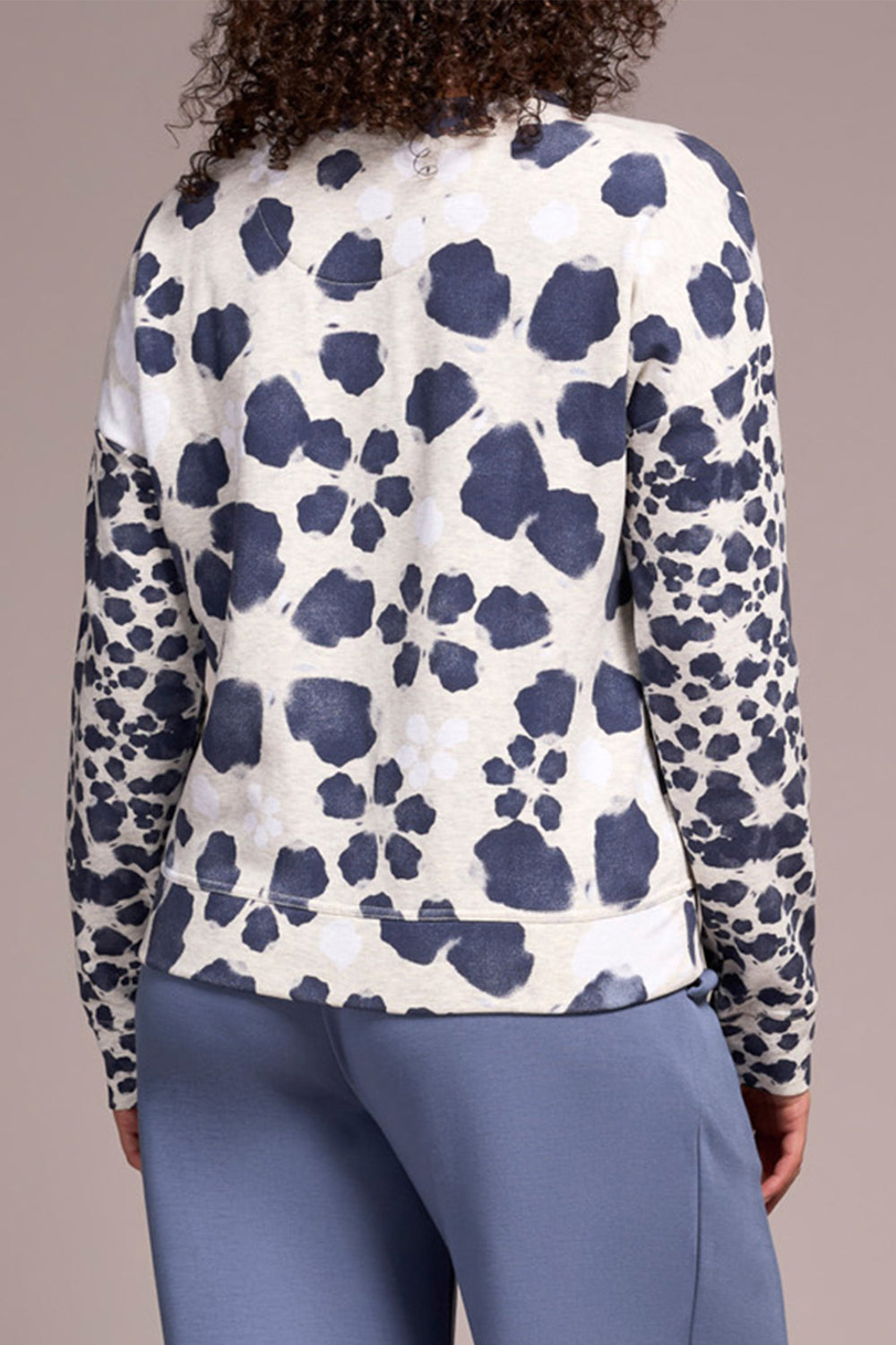 Person wearing a long-sleeve top with a blue and white pattern on a plain background