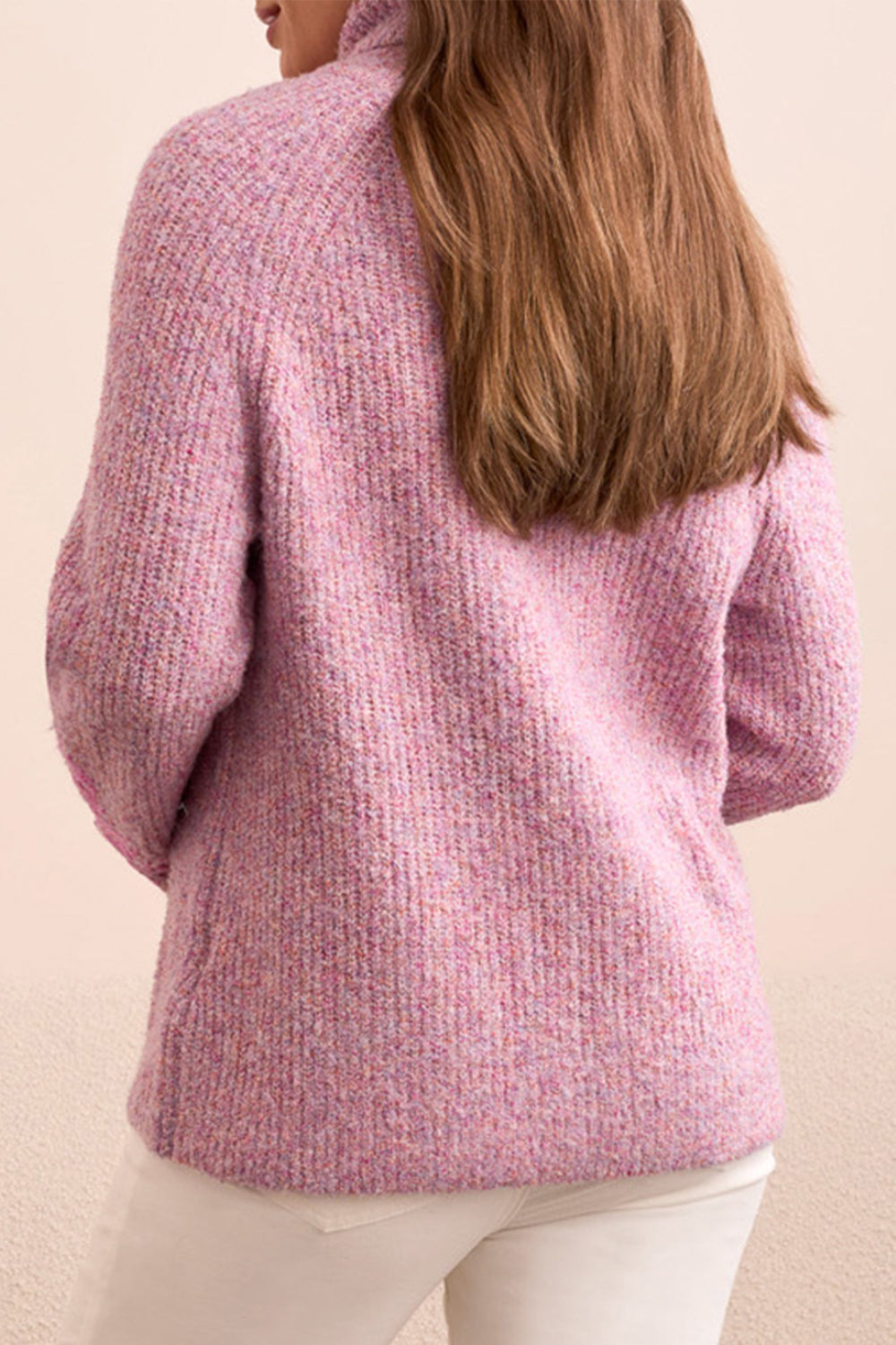 Person wearing a pink textured sweater against a beige background